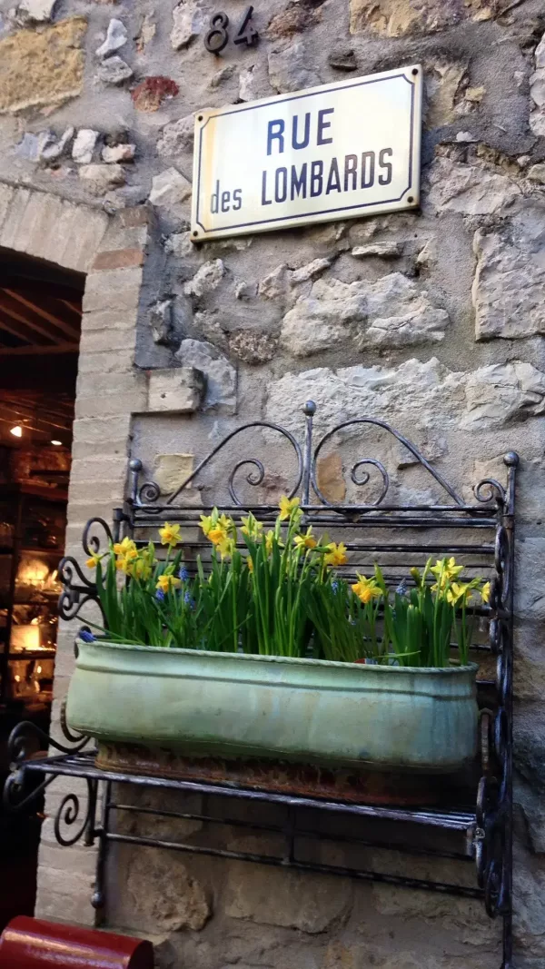 une ruelle de mougins avec sa signaletique et une decoration florale en metal avec des jonquilles printanieres, un des villages de france decrit par chantille de lincourt 